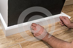 Close up of mans hands fitting skirting board