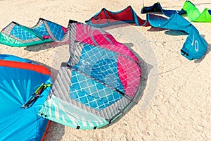 Close-up many bright kitesurf wings and kite equipment sand beach shore watersport spot on bright sunny day against sea