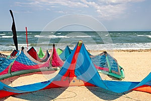 Close-up many bright kitesurf wings and kite equipment sand beach shore watersport spot on bright sunny day against sea