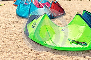 Close-up many bright kitesurf wings and kite equipment sand beach shore watersport spot on bright sunny day against sea