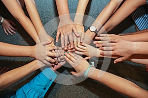 Close-up of many children`s hands holding together as a team on a nature background