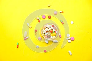 Close up of many colorful pills and capsules on yellow