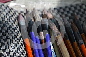 Close-up of many multicolored brushes lying on a chess mat and ready to paint, selective focus