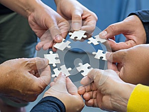 Close-up of many people hands holding a jigsaw puzzle piece in circle together