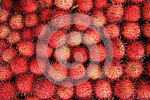 A close up of many red ramboutans in a Thai market