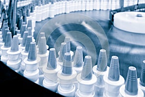 Close-up Many white plastic spray bottles for packaging liquid medicines or cosmetics in a row on a conveyor belt in a pharmaceuti