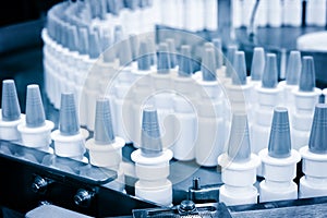 Close-up Many white plastic spray bottles for packaging liquid medicines or cosmetics in a row on a conveyor belt in a pharmaceuti