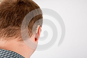 Close up of a manâ€™s ear wearing hearing aid viewed from back.