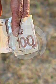A close up of a manâ€™s hand holding Canadian money
