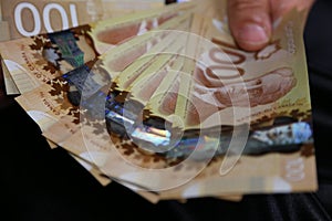 A close up of a manâ€™s hand holding Canadian money