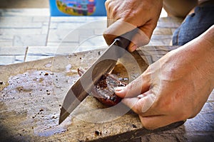 Close up manâ€™s hands are cutting roasted meat on a wooden chop