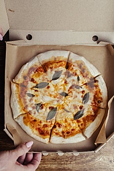 Close-up of Margarita pizza in a disposable dish. Top view of takeaway food in a fast food cafe. On photo - mozzarella cheese,