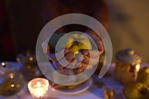 Close up of masculine hands holding quince on dark background