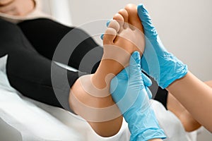 Close up masseur doing massage of feet at beauty salon to woman