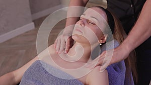 Close up of masseuse hands massaging female face. Woman closed eyes with pleasure.