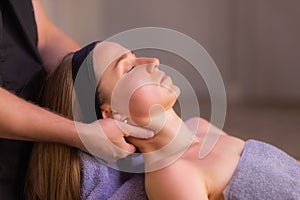 Close up of masseuse hands massaging female face. Woman closed eyes with pleasure.