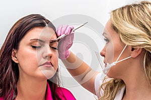 Close-up of a master drawing a shape of a eyebrow with a white pencil photo