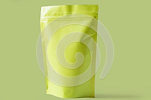 Close up of matt green paper doypack stand up packaging pouch with zipper on light green background