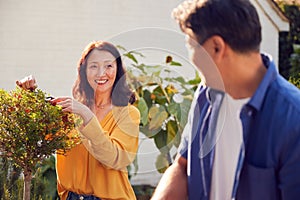 Close Up Of Mature Asian Couple At Work Watering And Pruning Plants In Garden At Home