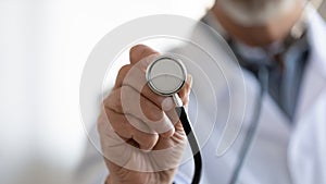 Close up mature doctor holding stethoscope, medical checkup