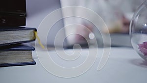 Close-up of mature female Caucasian hand taking red pen laying at the table. Blurred Caucasian woman using laptop at the