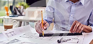 Close Up Of Mature Male Architect Working In Office At Desk Studying Plans For New Building