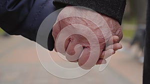 Close-up of a mature male Caucasian hand holding child`s palm. Unity of grandfather and granddaughter.