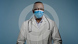 Close-up mature male doctor surgeon in protective mask looks at camera man experienced hospital worker posing in studio