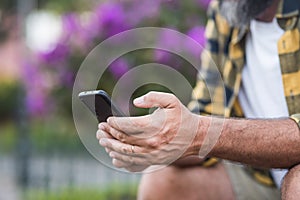 Close up of mature man hands typing and writing on a mobile phone. Male hands people using app on smartphone outdoor. Concept of