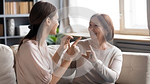 Close up mature mother and grownup daughter speaking sign language