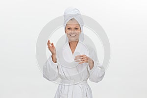 Close-up of a mature woman in a white bathrobe with a towel on her head applies