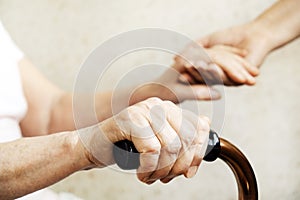 Close up of mature womans & nurse hands. Health care giving, nursing home. Parental love of grandmother. Old age related diseases.