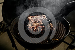 Close-up of meat on grill which professional male cook accurate turns using tongs.