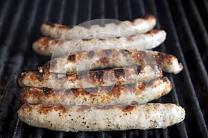 Close-up of meat sausages sizzling on a gas BBQ grill, BBQ in the garden,