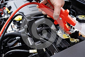 Close-Up Of Mechanic Attaching Jumper Cables To Car Battery