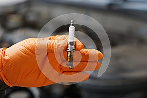 Close up mechanic hands hold old spark plug, spare part of car engine