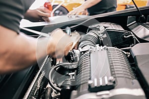 Close-up of a mechanic& x27;s hand repairing the car engine in a garage