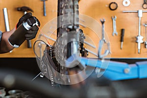 close up of a mechanic's hand wearing gloves using chain lube lubricating the chain and freewheel