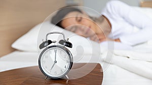 Close up mechanical alarm clock standing on bedside wooden table.