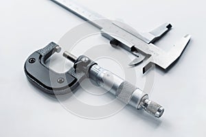 Close-up of a mechanical micrometer and caliper on a light background