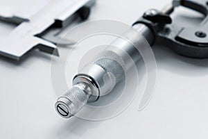 Close-up of a mechanical micrometer and caliper on a light background