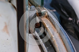 A close-up of the mechanism and joints of a shower stall screen with mold, limescale and mildew. Dirty disgusting shower