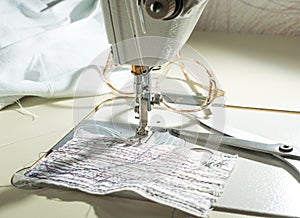 close-up of mechanism with a needle of an electric sewing machine. against the background of glasses and fabric with