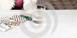 Close-up of medical bright colored blisters with pills and capsules with medicines and a glass of water. Pills from the first-aid