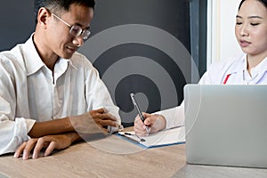 Close up medical doctor in white uniform gown coat interview and filling up an application form while consulting patient, medical