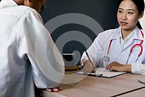 Close up medical doctor in white uniform gown coat interview and filling up an application form while consulting patient, medical