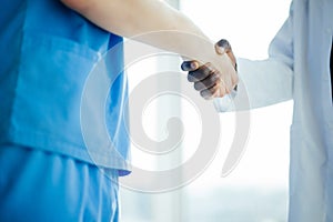 Close up of Medical handshake. Doctoral meeting. Two confident doctor standing in hospital and discuss the patient and shake their