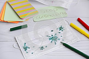 Close-up of a medical mask with a children`s drawing of the virus molecule with colored felt-tip pens