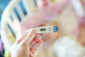 Close-up medical thermometer, Parent measuring temperature of ill kid, 1 years old toddler girl gets high fever lying on bed.