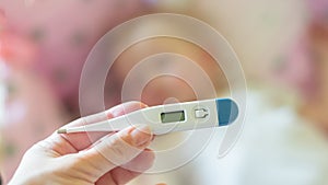 Close-up medical thermometer, Parent measuring temperature of ill kid, 1 years old toddler girl gets high fever lying on bed.